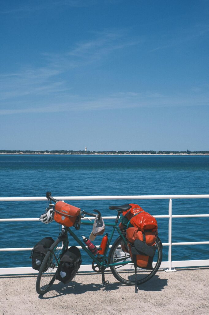 Bicycle parked beside Arcachon Bay with vibrant packs, perfect travel and cycling scenery.