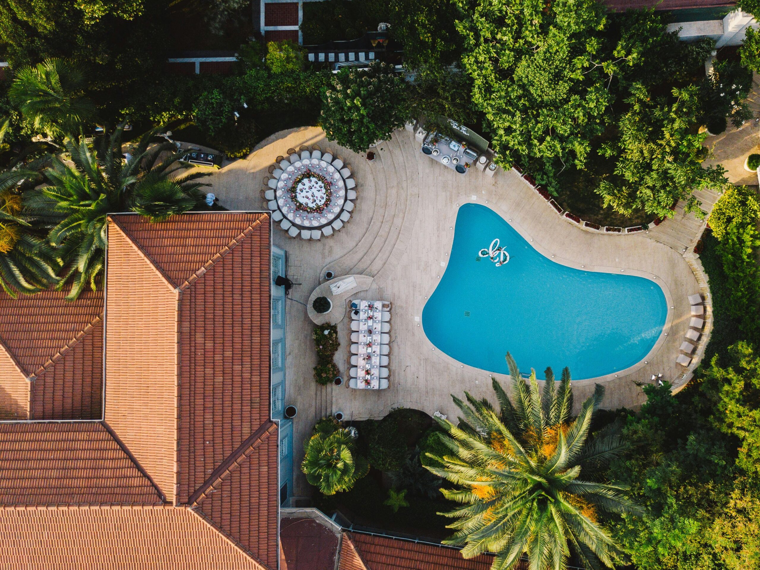 A stunning birds-eye view of a tropical resort featuring a swimming pool and lush greenery.